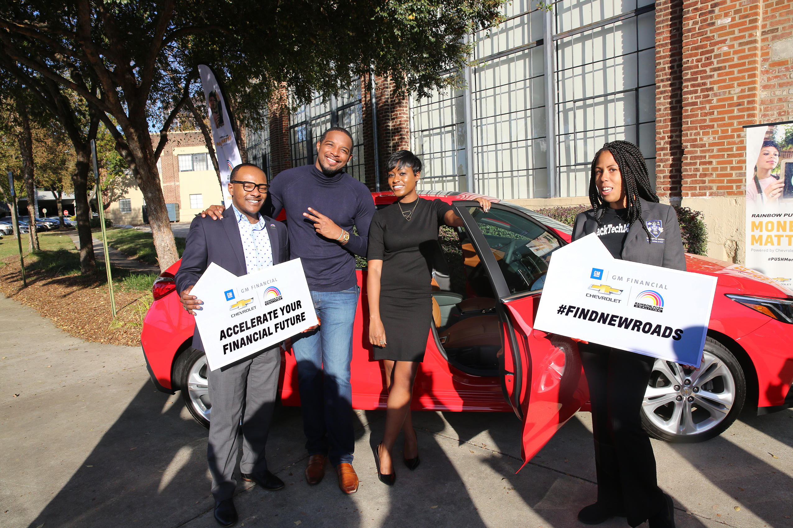 Attendees by red Chevrolet with Accelerate Your Financial Future signs